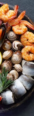 Seafood charcuterie platter board with shrimp, oysters, fish and octopus on black background. Top view, close up